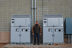 Tom Troiano, warehouse manager of Allan S. Goodman helped overse the installation. He is shown standing between the system's two inverters. Solar inverters convert the panel output into useable electricity.