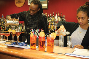 Derrick Edmondson with classmate Naomi Robinson mixing cocktails during class practices.