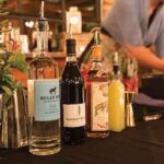 The lineup of products to make “The Olympia Spritz.” The recipe from Nostrand is as follows: 1.5 oz. Bully Boy Vodka; .5 oz. Jules Theuriet Crème de Cassis; .5 oz. Pierre Ferrand Dry Curaçao; .25 oz. fresh pressed lemon juice; 2 oz. of Newport Vineyards Brut 2014. Shake vodka, cassis, dry curaçao and fresh lemon juice over ice; pour over fresh ice into a wine glass. Top with Brut. Garnish with fresh herbs or edible blossoms.