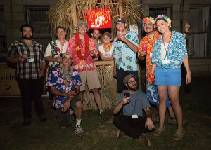 First row standing: Zach Davis, Visitors Center Staff; Derek Luke, Co-Founder and Brewmaster; Brent Ryan (pink Hawaiian shirt and bucket hat): Co-Founder and Master Distiller; two Tiki Hut volunteers; Jason Tsangarides, Brewer; Joe Welch, Rhode Island Sales Representative; and Clare Simpson-Daniel, PR & Events Coordinator. Second row: Pete Lanouette, Brewer and Distiller and Riley Mello, Visitors Center Manager, all with Coastal Extreme Brewing Company.