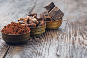 Dark chocolate pieces, cocoa powder and cocoa beans on a wooden