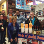 Five out of the six customers who won the raffle for a chance to purchase the elusive whiskies, and kneeling in front is Molly Newton, of Friends of Assisi Food Pantry, who led the raffle drawing.