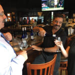 Michael Schlink speaking with Tony Scacca, who is pouring wine for Gina Scacca. The Scaccas own First & Last Tavern in Middletown. 